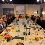 Filipino nurses enjoying a communal dinner with Towne Kids in a modern, warmly lit venue.